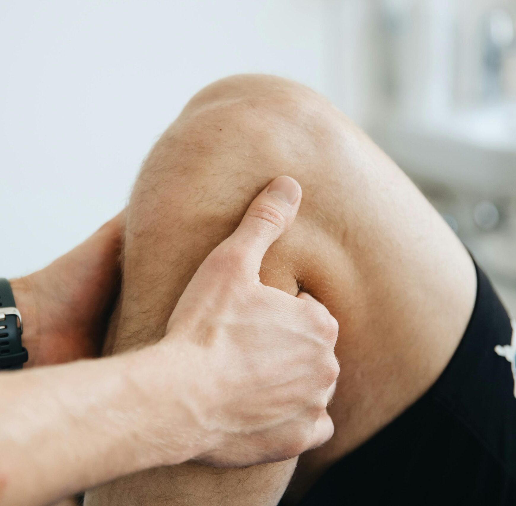 Close-up of a physiotherapist massaging a patient's knee during therapy.